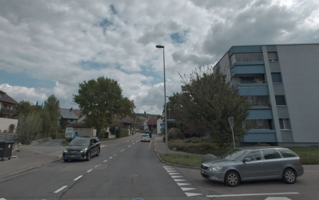 Blick in Fahrtrichtung der Grüstrasse in Gossau, auf der linken Fahrspur kommt ein Auto entgegen, ein zweites Fahrzeug von rechts ist nicht vortrittsberechtigt und hat angehalten. Im Hintergrund sind Wohnhäuser zu sehen. 