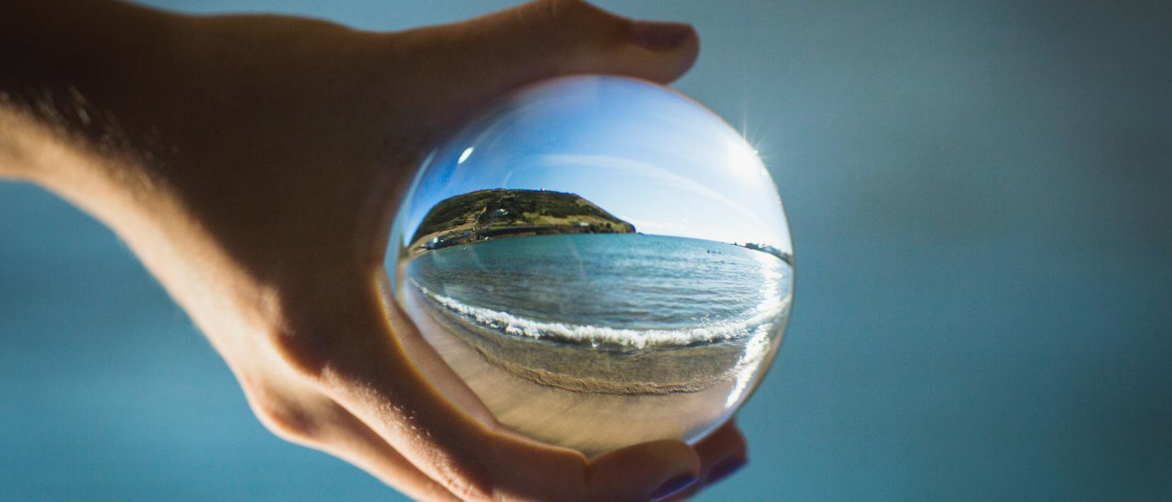 Eine Uferlandschaft durch eine Glaskugel hindurch fotografiert.