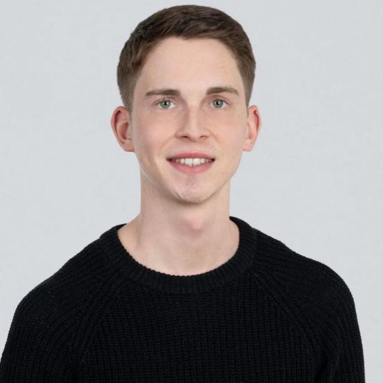 Ein Portraitbild, das unseren Mitarbeiter mit kurzen Haaren und einem schwarzen Pullover zeigt