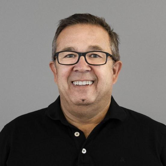 Ein Portraitbild eines Mannes. Er hat kurze braune Haare und trägt eine Brille mit dunklem Rand. Er trögt ein graues Poloshirt sowie einen schwarzen Pullover.