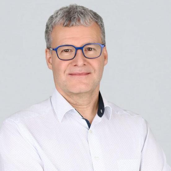 Ein Portraitbild, das unseren Mitarbeiter mit kurzen Haaren, Brille und einem weissen Hemd zeigt