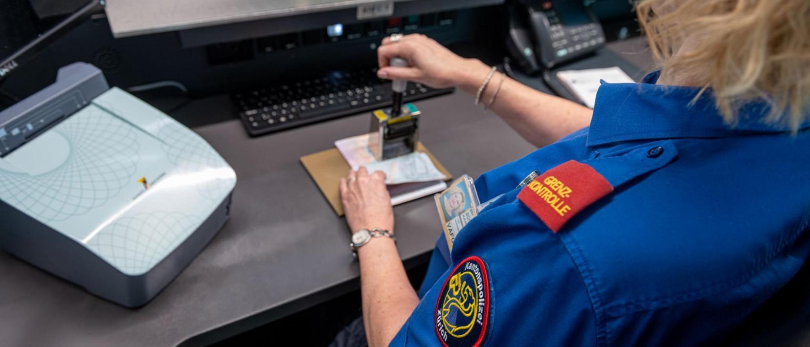 Eine Sicherheitsassistentin der Grenzkontrolle stempelt einen Pass.