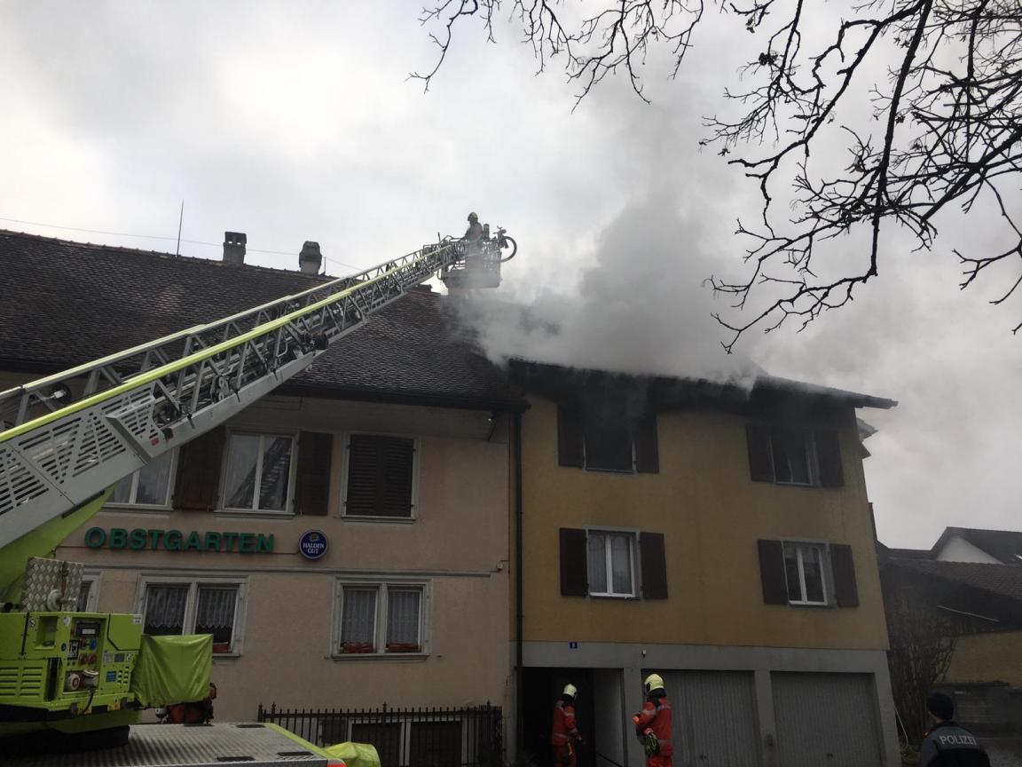 Brandort: Das brennende Haus  und die Feuerwehr bei der Brandbekämpfung.