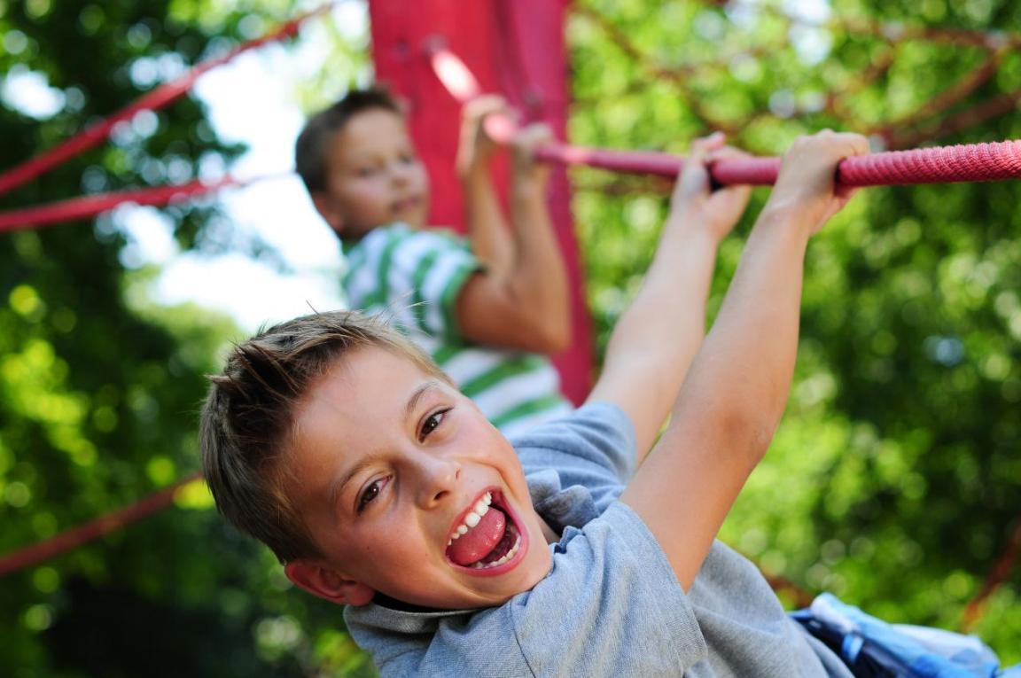 «Kinder aktiv»: Zwei Knaben halten sich mit beiden Händen an einem roten Seil auf einem Spielplatz fest.