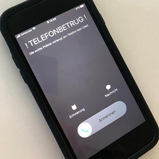 Schriftzug Telefonbetrug - Die echte Polizei verlangt am Telefon kein Geld auf Mobiltelefon Bildschirm