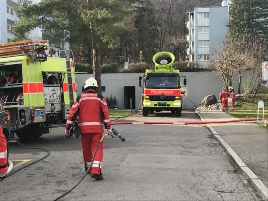 Foto eines Feuerwehrmannes mit Löschschlauch in der Hand vor Tiefgarage