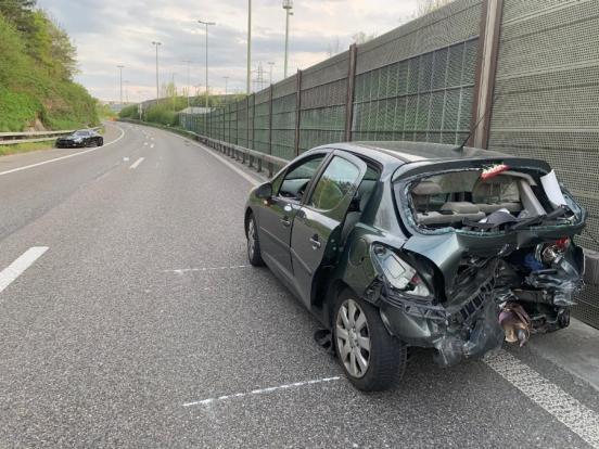 beteiligtes Unfallfahrzeug mit beschädigtem Heck steht am rechten Fahrbahnrand der rechten Spur