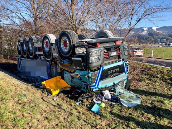 Lastwagen liegt auf dem Dach in Wiese neben Autobahnausfahrt