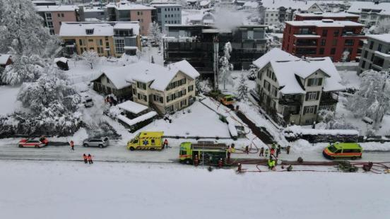 Diverse Einsatzfahrzeuge vor einem Gebäude, aus welchem Rauch aufsteigt