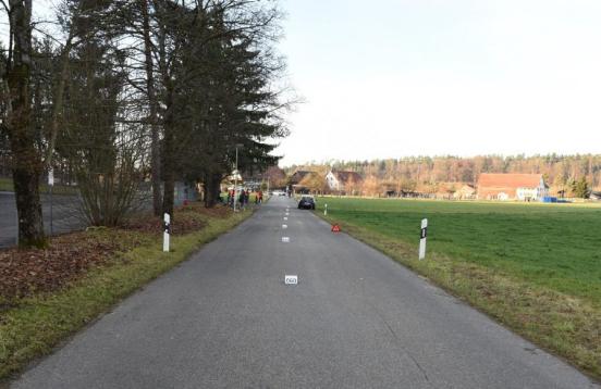 Gerade Strasse mit Spurensicherungstafeln und PW im Hintergrund