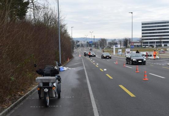 Elektrisches Kleinmotorrad nach Verkehrsunfall auf Trottoir stehen, Verkehrsleitung an der Unfallstelle vorbei