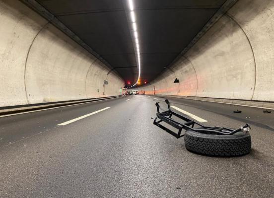Abgerissenes Reserverad liegt auf der Fahrbahn im Uetlibergtunnel. Im Hintergrund ein Unfallfahrzeug.