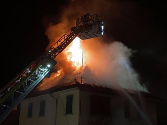 Dachstock eines Gebäudes in Brand und Feuerwehren beim Einsatz