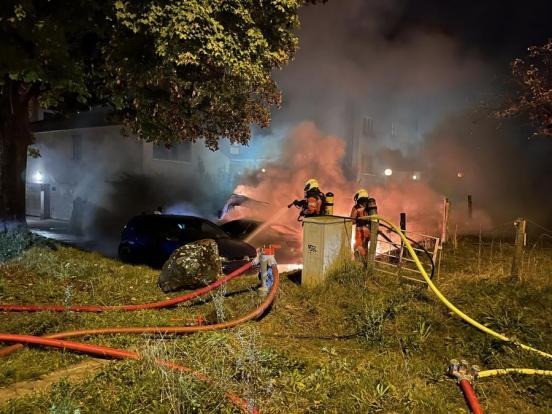 Zwei Feuerwehrleute löschen den Fahrzeugbrand