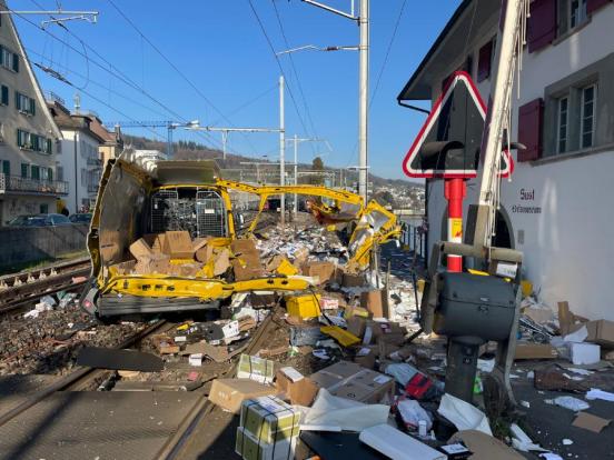 Völlig zerstörter Lieferwagen auf dem Bahngleis und viele Pakete verteilt