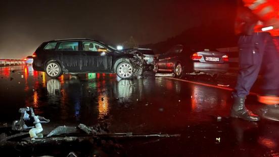 Beschädigte Unfallfahrzeuge stehen auf der nassen Fahrbahn der Autobahn