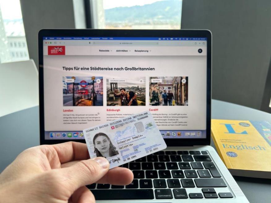 Lapto mit einer Reiseseite von Grossbritannien und im Vordergrund eine Schweizer Identitätskarte
