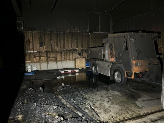 In einer durch ein Feuer verrussten Halle steht ein ebenfalls russschwarzer elektrisch angetriebener Kleintransporter