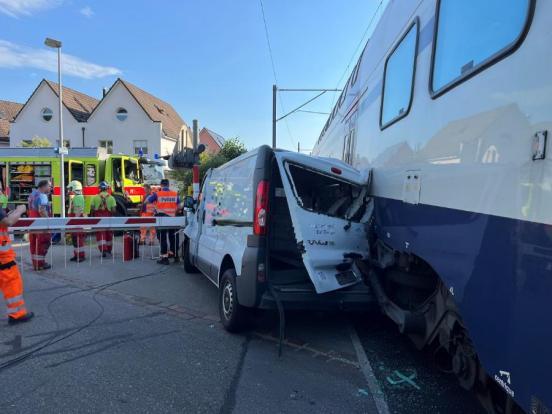Der verunfallte Lieferwagen steht mit eingedrückten Heck zwischen dem Zug und der Barriere