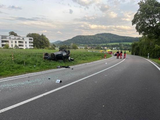 Das verunfallte Auto liegt neben der Strasse in der Wiese auf dem Dach