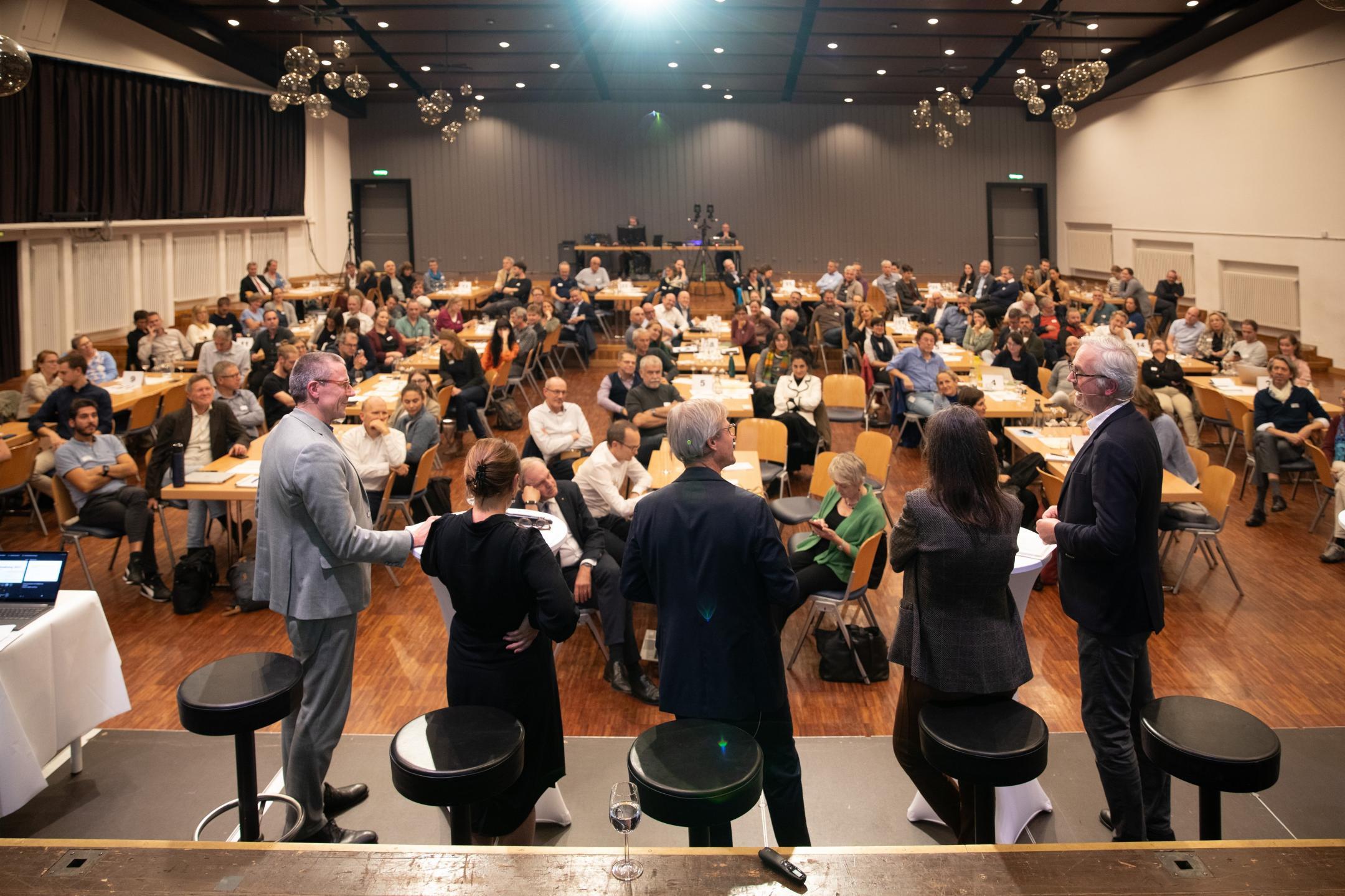 Blick von der Bühne über die Podiumsteilnehmenden hinweg auf das Publikum.