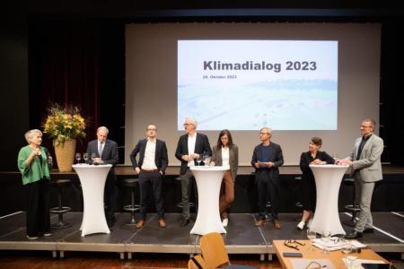 Die Gastgebenden und die Podiumsteilnehmenden diskutieren auf der Bühne.