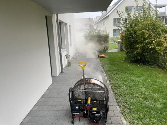 Rauch dringt aus Schacht, daneben steht Entlüfter