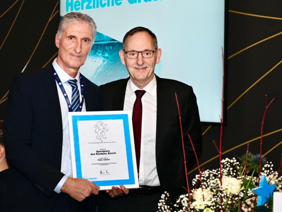 Regierungspräsident Mario Fehr überreicht Peter Zahner, CEO der ZSC Lions AG die Urkunde des Sportpreises des Kantons Zürich vor den geladenen Gästen.