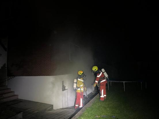 Feuerwehrleute mit Atemschutz vor einem Haus mit Rauch