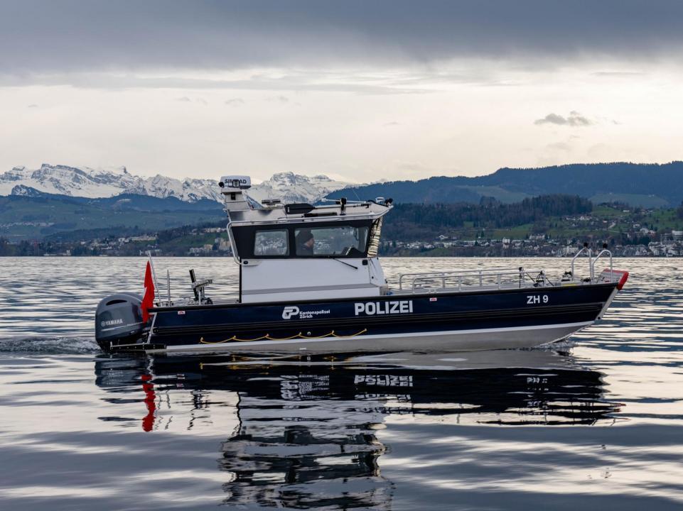 Das Schiff fährt langsam auf dem Zürichsee. Auf der Seite ist es mit Polizei beschriftet und trägt das Logo der Kantonspolizei Zürich