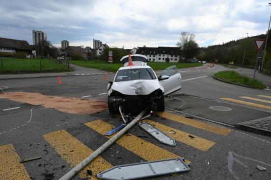 Ein Auto mit eingedrückter Front das auf einem umgefahrenen Beleuchtungsmasten steht.