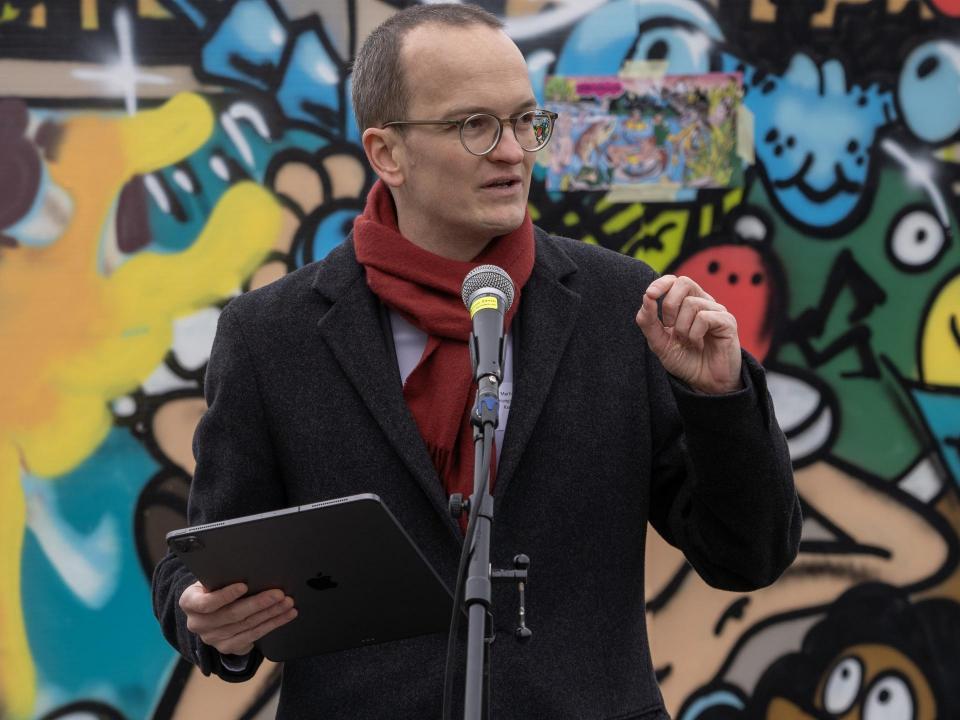 Martin Neukom hält eine Rede. Im Hintergrund ein buntes Graffito.