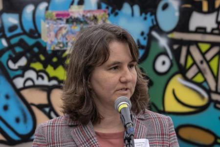 Simone Brander hält eine Rede. Im Hintergrund ein buntes Graffito.