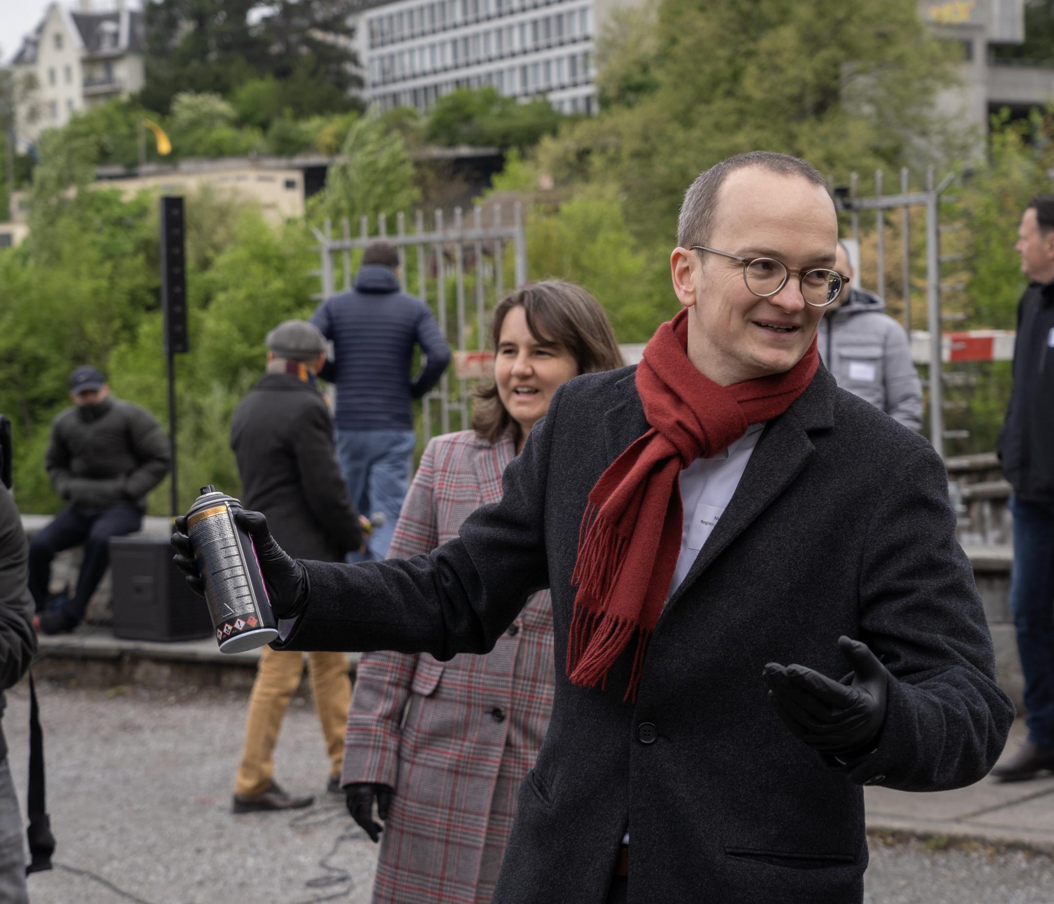 Regierungsrat Martin Neukom am Platzspitz mit Spraydose in der Hand. Im Hintergrund Journalisten und Gäste.