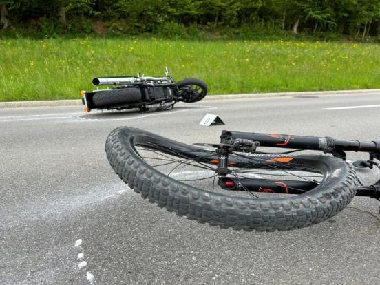 Verbogenes Velovorderrad. Im Hintergrund ein auf der Strasse liegendes Motorrad