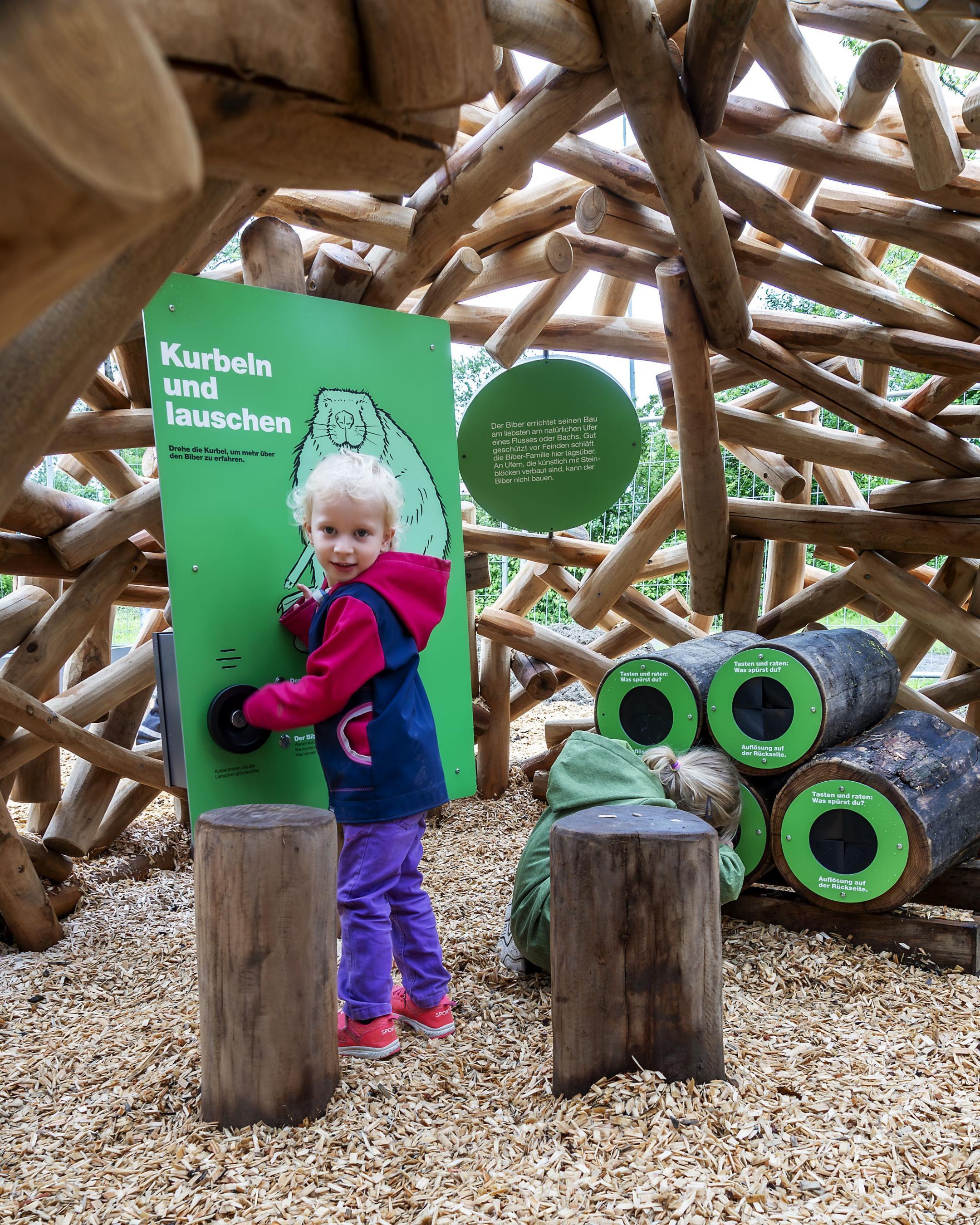 Ein kleines Kind dreht an einer Hörstation die Kurbel, um sie in Betrieb zu setzen