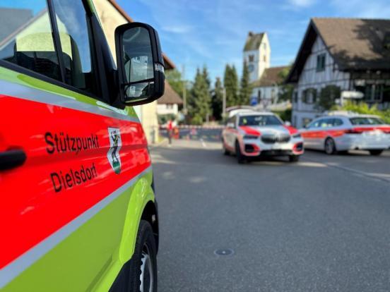 Seitentür eines Feuerwehrfahrzeugs; Im Hintergrund Polizeifahrzeuge auf der Strasse und eine abgesperrte Unfallstelle