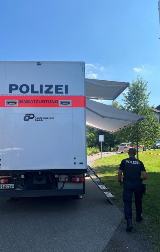 Die Mobilie Einsatzzentrale der Kantonspolizist steht auf einem Platz und ein Polizist läuft davon