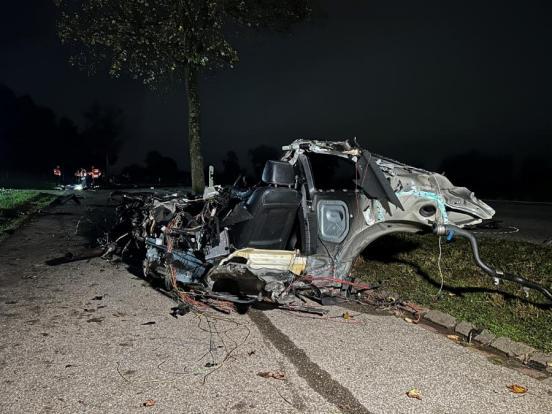 eine Hälfte des komplett zerstörten Unfallfahrzeuges auf der Strasse bei Nacht