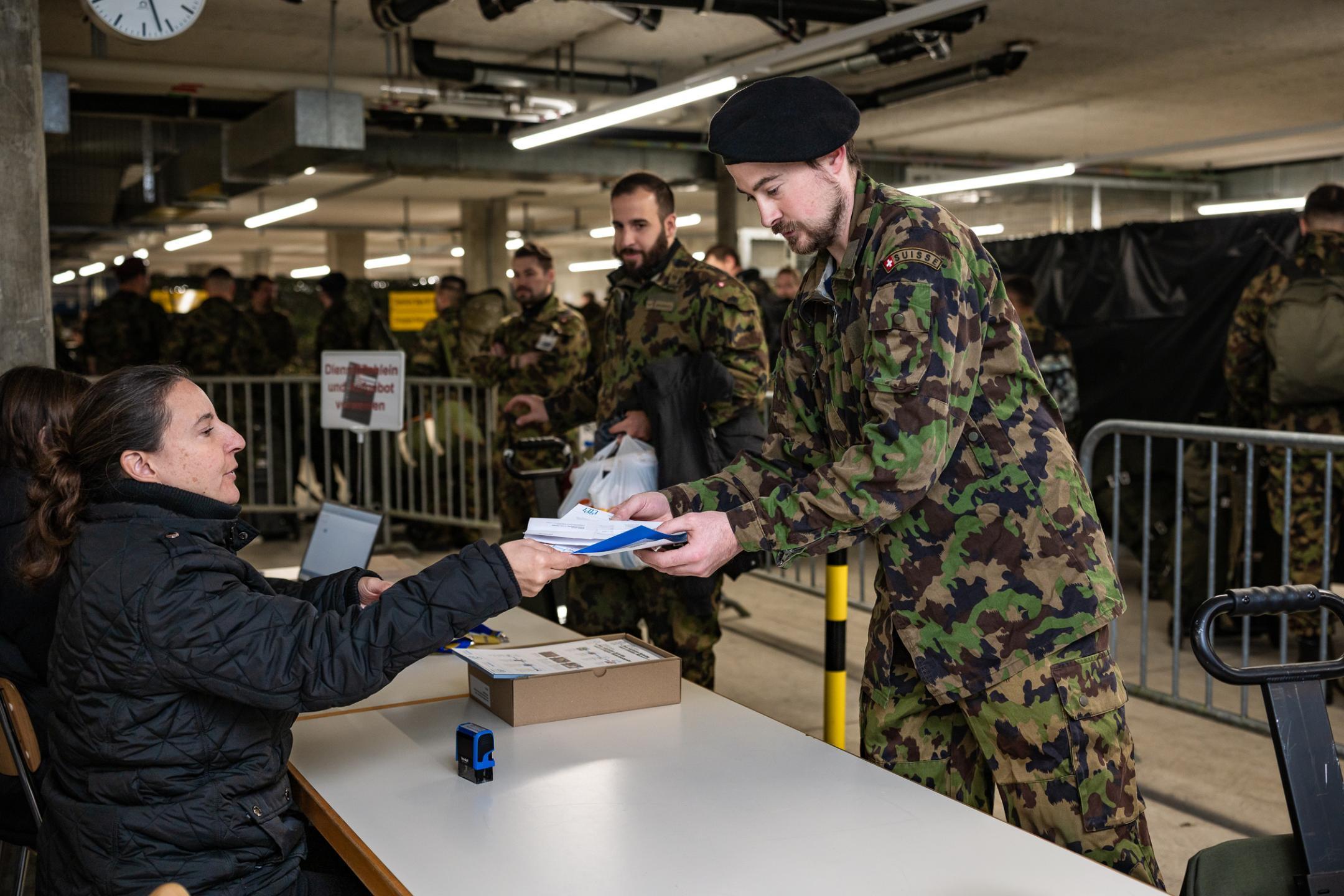 Ein Armeeangehöriger erhält von einer Mitarbeiterin eine schriftliche Bestätigung in die Hände, dass er sein Material offiziell abgegeben hat.