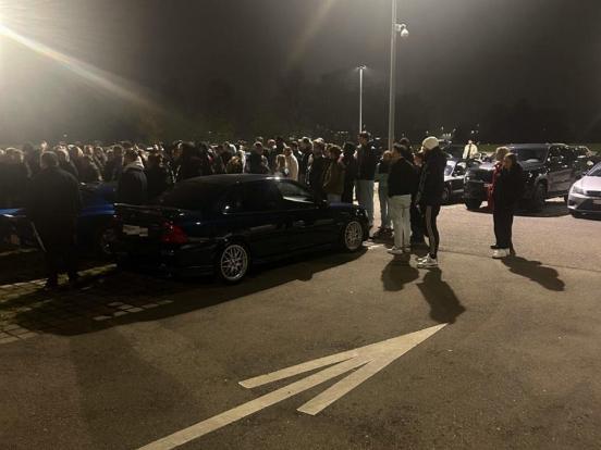 Getuntes Fahrzeug und viele Personen bei Nacht auf einem Parkplatz