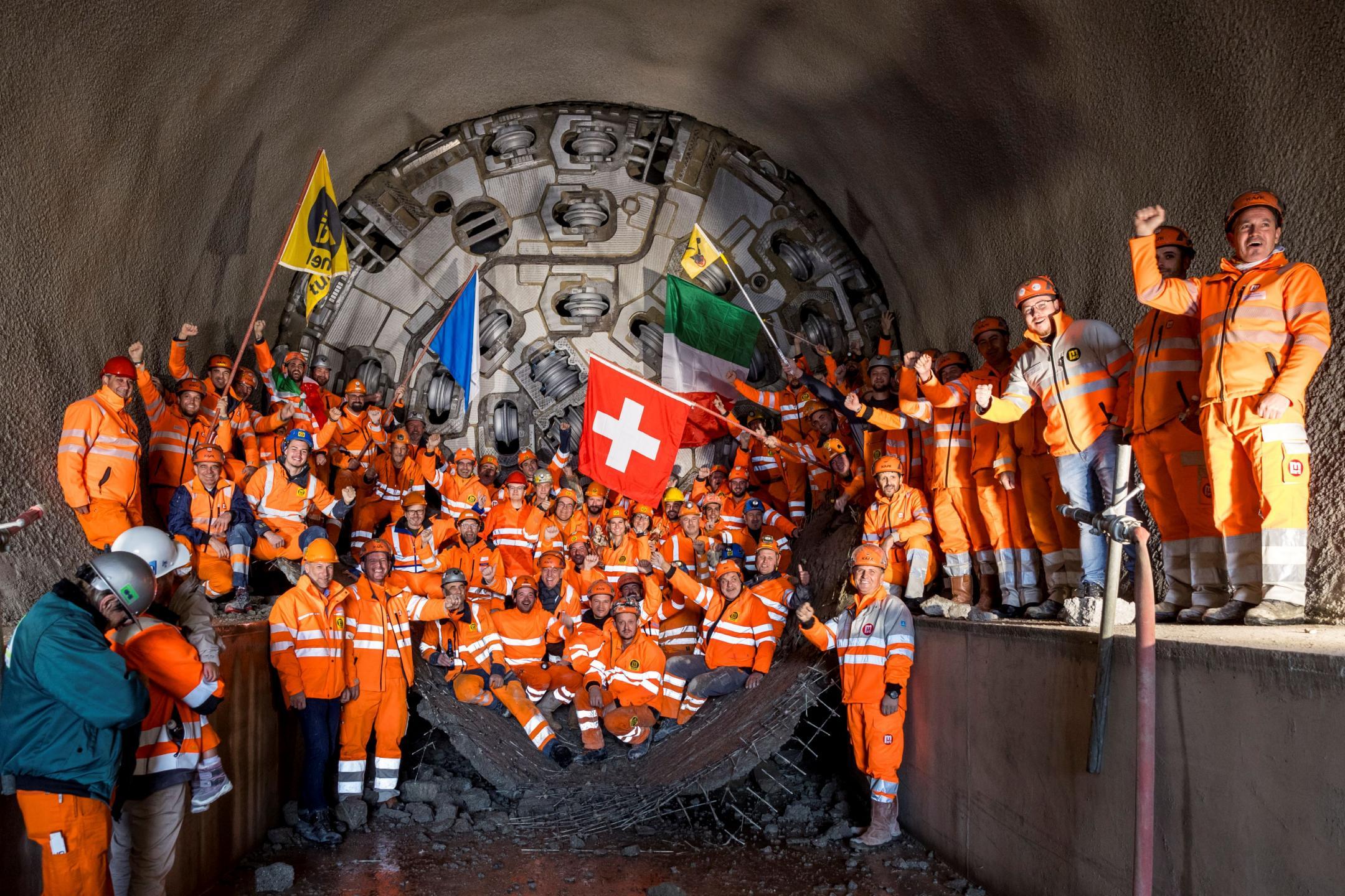 Ein Gruppe von Mineuren und Regierungsrat Martin Neukom feiern vor dem Bohrkopf den erfolgreichen Durchstich