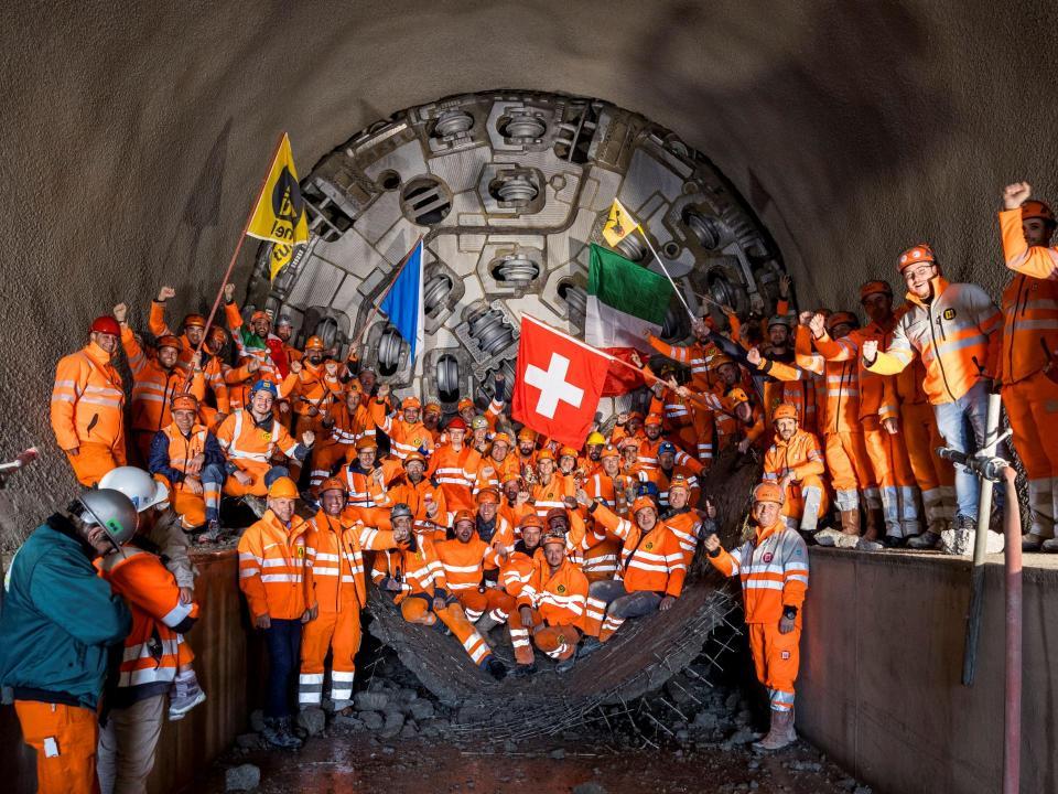 Ein Gruppe von Mineuren und Regierungsrat Martin Neukom feiern vor dem Bohrkopf den erfolgreichen Durchstich