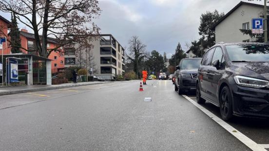 An der Unfallstelle sind Polizisten am Arbeiten, am rechten Strassenrand stehen parkierte Fahrzeuge