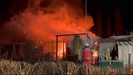Gartenhäuschen in Vollbrand; Feuerwehrmänner im Vordergrund