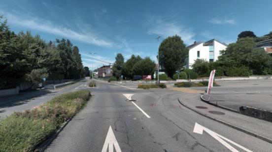 Strassenkreuzung mit Grünflächen in der Mitte und weissen Markierungen.