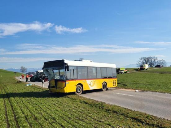 Ein beschädigtes Postauto auf der Strasse, im Hintergrund der beschädigte Traktor