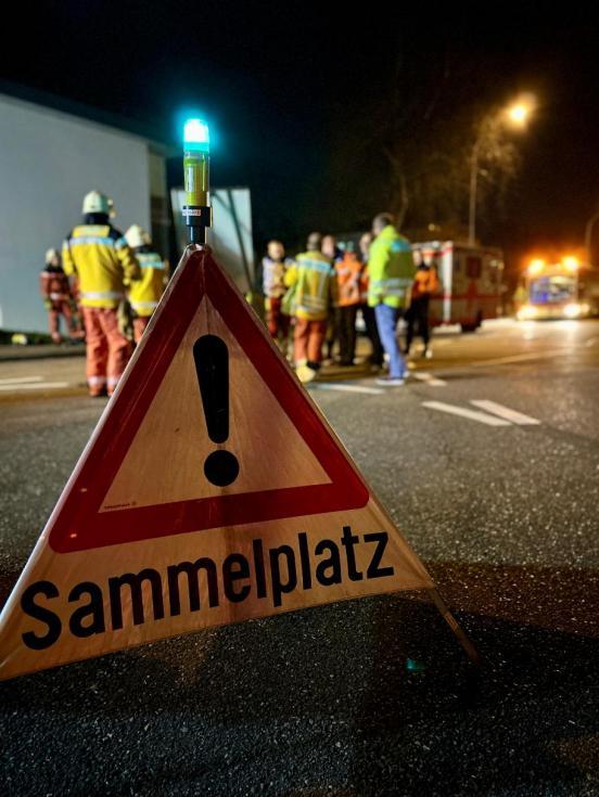 Im Vordergrund ein Triopan mit der Aufschrift Sammelplatz, im Hintergrund mehrere uniformierte Personen