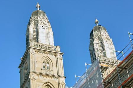 Zwei Türme des Grossmünsters in Zürich teilweise eingerüstet mit weissem Netz, unte