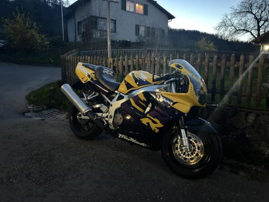 Gelb schwarzes Motorrad vor einen Gartenzaun